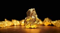 Visual representation of a large gold nugget sitting afore a black background.