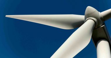 A ground-up perspective standing underneath a wind turbine.