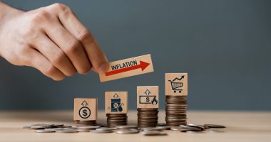 Hand putting wooden cube and inflation word a on coins