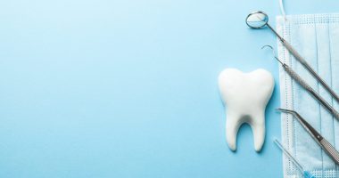 Tooth and dental instruments on blue background.