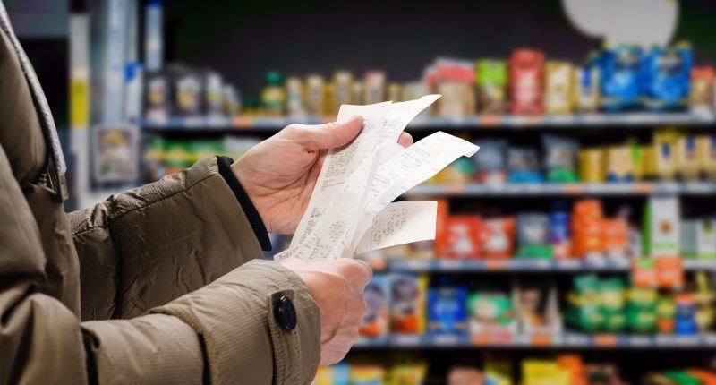 Image of a man checking prices on a receipt