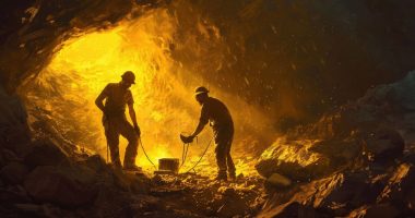 Two miners digging in a cave awash with gold light.