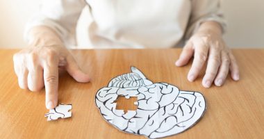 Elderly woman with a jigsaw puzzle representing the brain