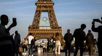 Tourists stand in front of the Eiffel Tower in Paris.