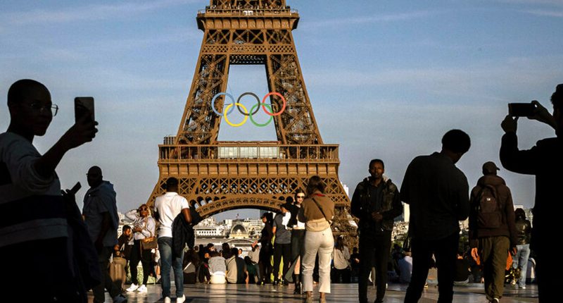 Tourists stand in front of the Eiffel Tower in Paris.