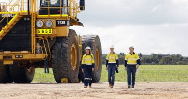 Three Iluka Resources workers walk away from a huge digger.