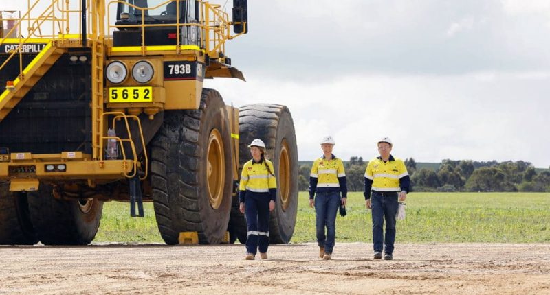 Three Iluka Resources workers walk away from a huge digger.