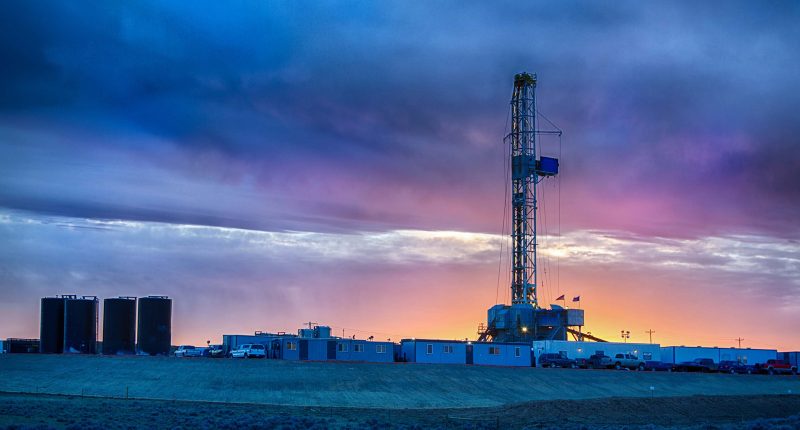 Brookside Energy facility far away on a hill in front of a red and blue sunset.