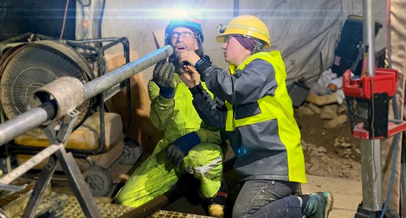 Two Resolution Minerals workers looking at a pipe in a mine.