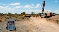 A drill rig set up to a "drilling in process" warning sign at Trek Metals' Christmas Creek Gold Project.
