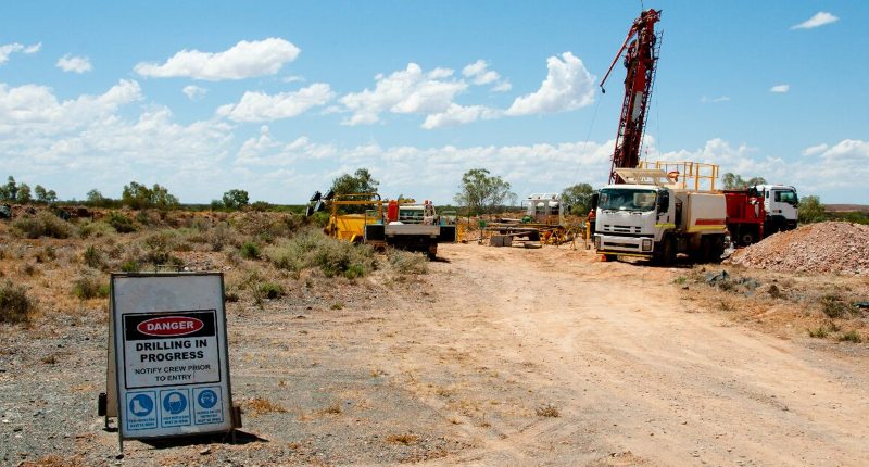A drill rig set up to a "drilling in process" warning sign at Trek Metals' Christmas Creek Gold Project.