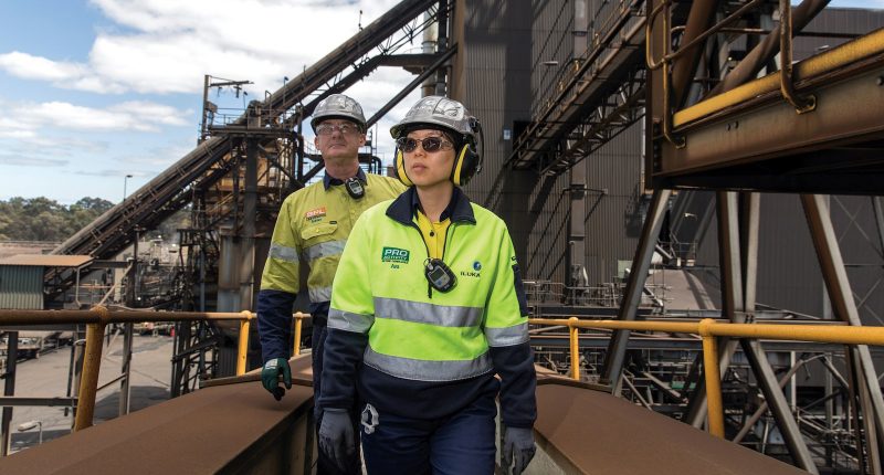 Two Iluka Resources in reflective gear walk through a construction site.