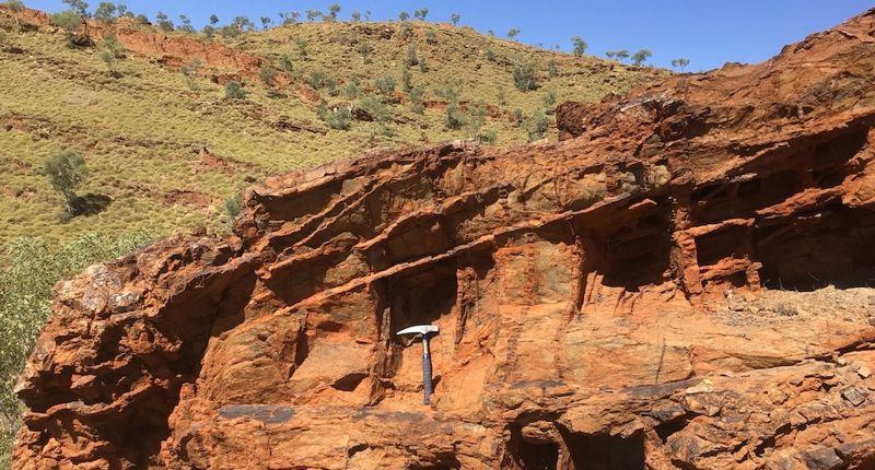 A rock face with a tool leaning against one outcrop.