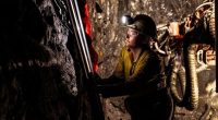 A gold miner in safety gear working at a Beacon Minerals mine shaft.