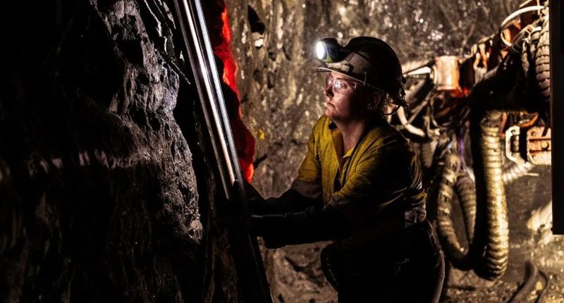 A gold miner in safety gear working at a Beacon Minerals mine shaft.