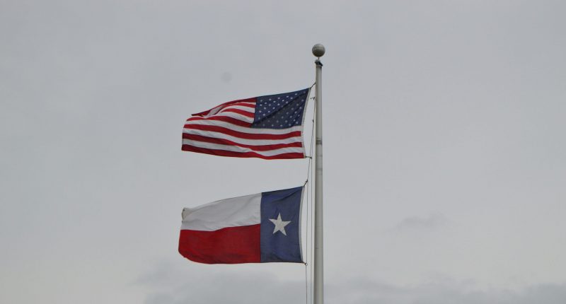 US flag atop Texas State flag