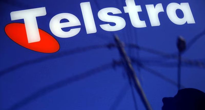 The Telstra logo seen in a deep blue sign reflected on a wall.