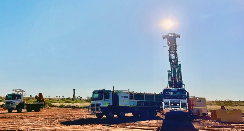 Two drilling trucks at Antipa Minerals' project. The sun sits just above the second working rig.