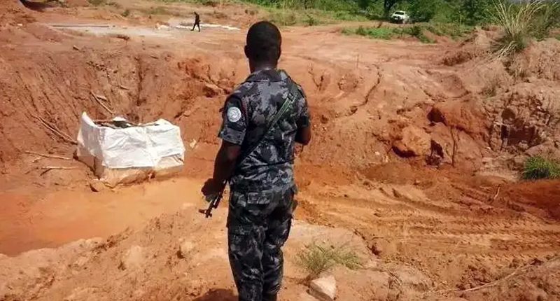 A guard with a rifle stands over Castle Mining's dig site in Ghana.