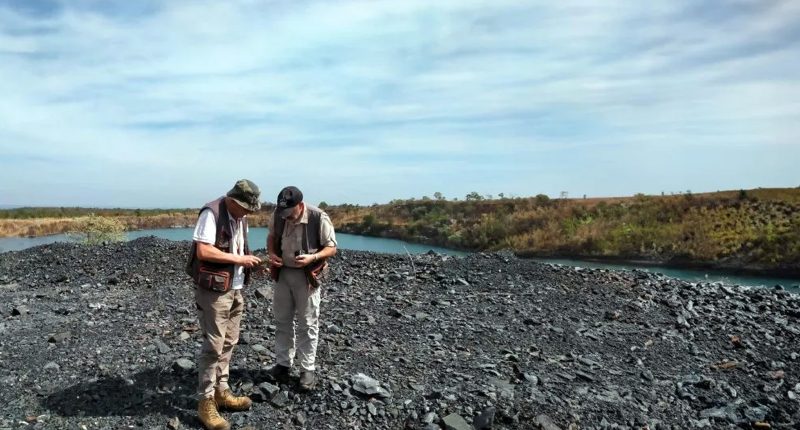 Two Desoto Resources workers stand on a deep-dark rocky plain.