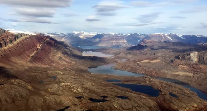 The Tannenberg copper project as seen from above. There's clouds hanging over brown mountains.