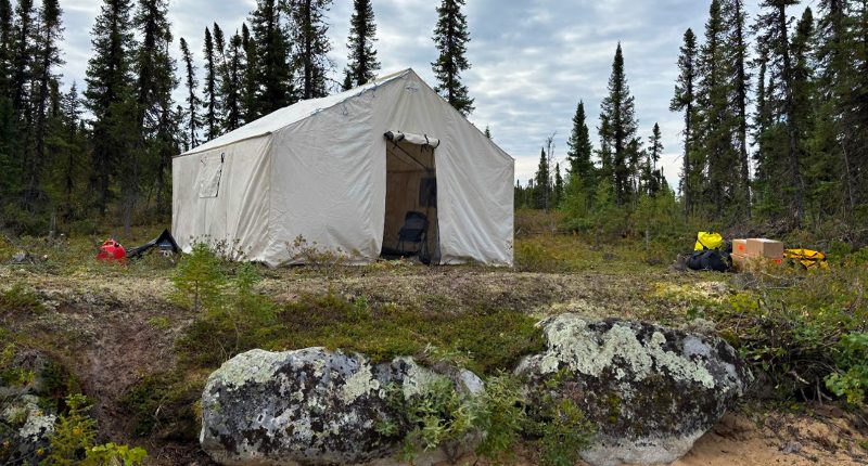 A mining tent is set up on a rocky outcrop.