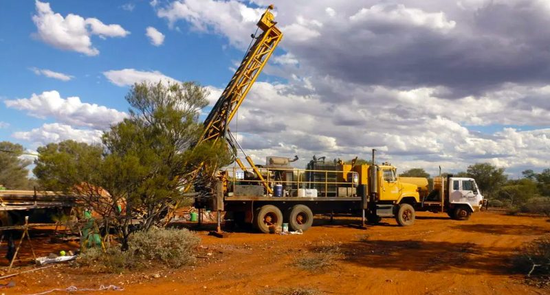 A mining rig and several trucks at an Abbotts Greenstone belt mining location.