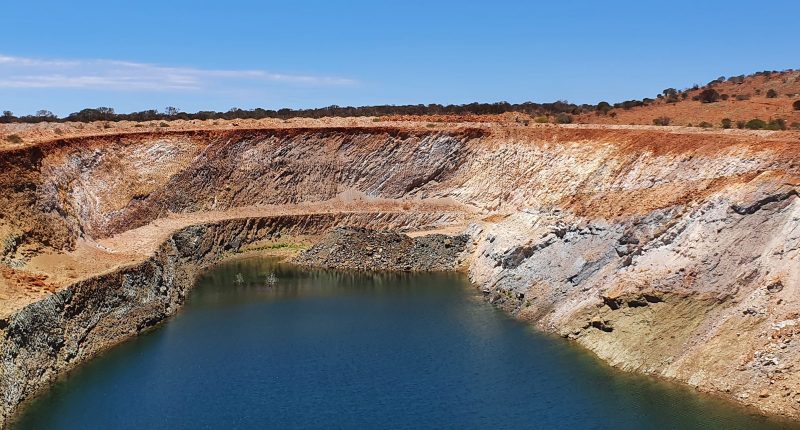 A blue lake surrounded by brown chalky rock banks.