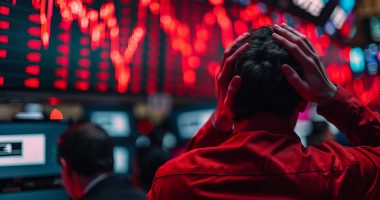 Wall Street investors, hands on head, gaze upward at red charts on crowded trading floor, conveying despair.