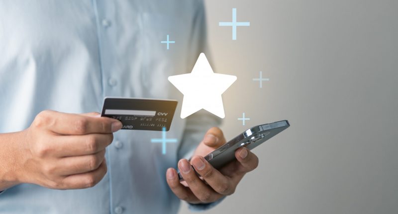 Hand holding credit card and smartphone with reward icon represents redeem points, loyalty programs, and cashback promotions.