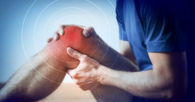 Detail of a representation of pain in the knee with red color on a bluish image. Side view.