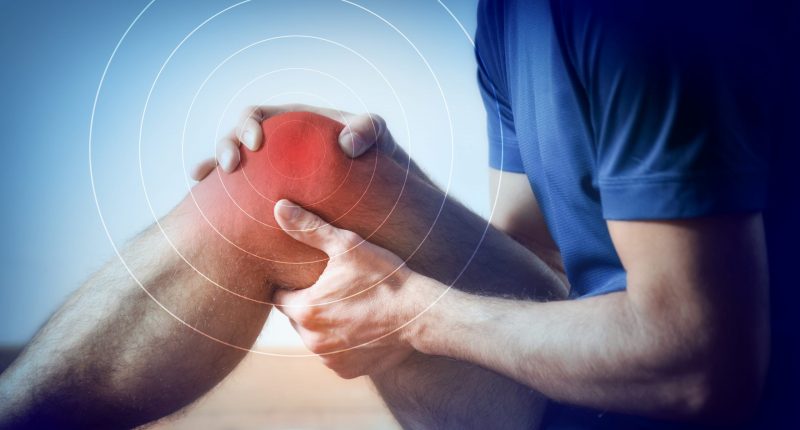 Detail of a representation of pain in the knee with red color on a bluish image. Side view.