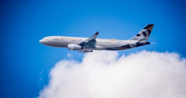 BRUSSELS, BELGIUM. 11th July 2018. Etihad Airways Airbus A330 in flight: A long distance shot of an Etihad Airways passenger airplane flying through a blue sky with soft white clouds. The aircraft features the Facets of Abu Dhabi livery.